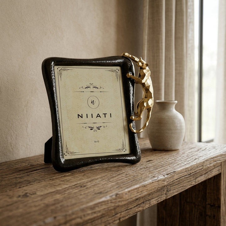 Black luxury photo frame with sculptural gold accent displayed on console